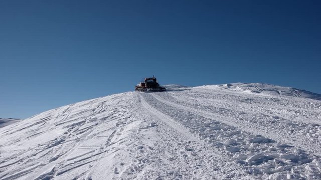 Skiers Riding on the Back of a Snowcat on a Snow Covered Mountain at a Winter Sunny Day