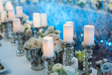 Wedding decor. Candles in candelabrum and roses. Blue background