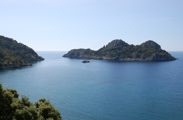Obraz premium Landscape with a small green island and pleasure boat in the calm blue lagoon.