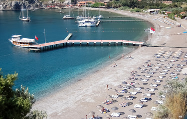 View of the beach, blue lagoon with clear water and a pier with pleasure boats.