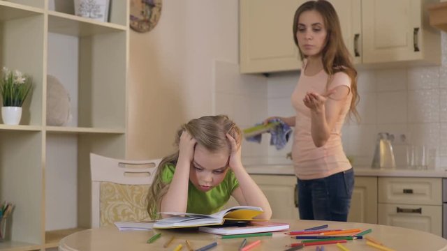 Strict mother criticizing daughter for mistakes in homework, lack of support