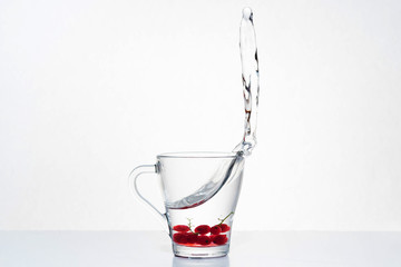 Glass of water and red cranberries with splash on a white background