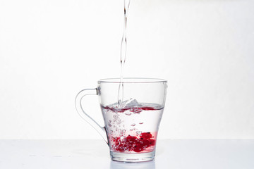 Glass of water and red cranberries with splash on a white background