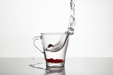 Glass of water and red cranberries with splash on a white background