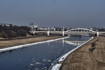 Urban landscape with river Warta, bridge and the cathedral towers in winter in Poznan.