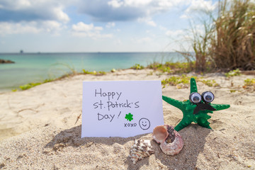 Green starfish with Happy St. Patrick day card at the beach.