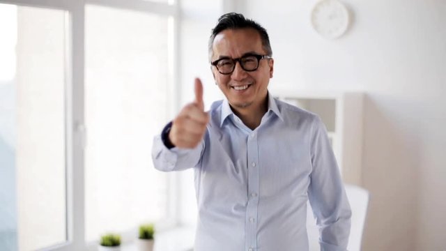happy businessman showing thumbs up at office