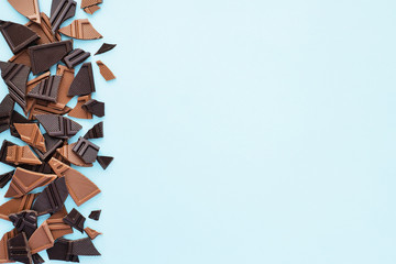 Broken milk and dark chokolate on blue background