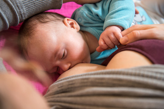 Mother holds her baby head while he is breastfed 