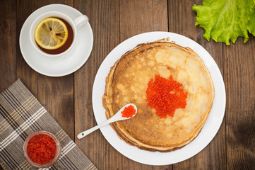 Pancakes with red caviar. Russian cuisine. Flat lay. Maslenitsa. Wooden background. Top view. Close-up