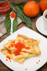 Pancakes with red caviar. Russian cuisine. Flat lay. Maslenitsa. Wooden background. Top view. Close-up