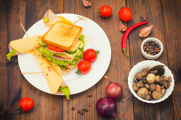 Big sandwich, meat, lettuce, cheese and vegetables on toasted. Wooden background. Top view. Close-up