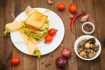 Big sandwich, meat, lettuce, cheese and vegetables on toasted. Wooden background. Top view. Close-up
