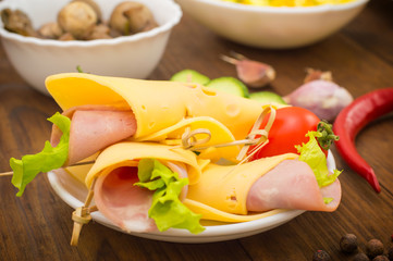 Slices canape with cheese, sausage, greens and tomato. Wooden background. Close-up