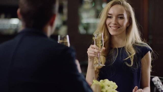 romantic pair cheering and drinking champagne in restaurant at the date