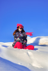 Happy girl sitting on top of a snowy mountain