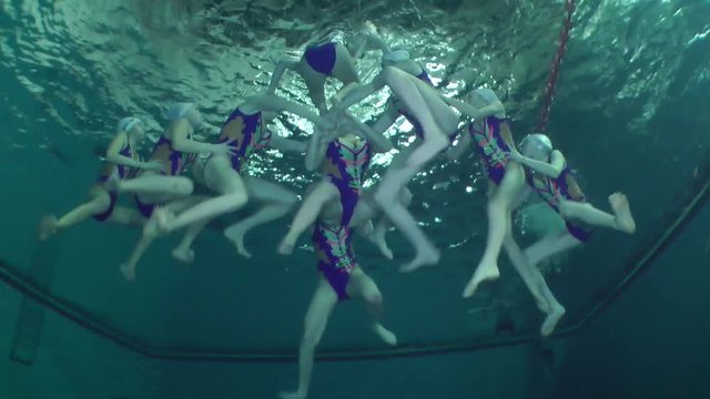 Synchronized swimming, team training, underwater view.
