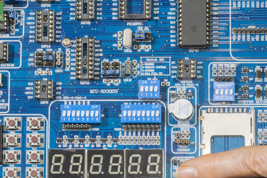 Una persona presiona el interruptor de una tarjeta de programacion de microcontroladores