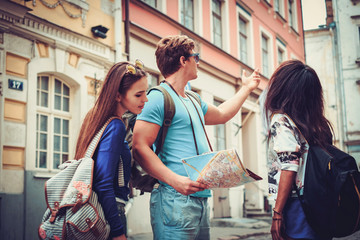 Multi ethnic friends tourists with map in old city