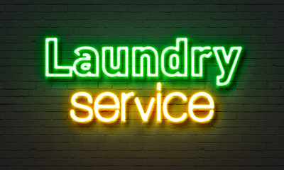 Laundry service neon sign on brick wall background.