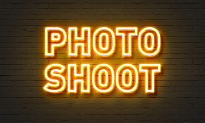 Photo shoot neon sign on brick wall background.