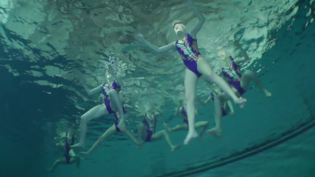 Synchronized swimming, team training, underwater view.
