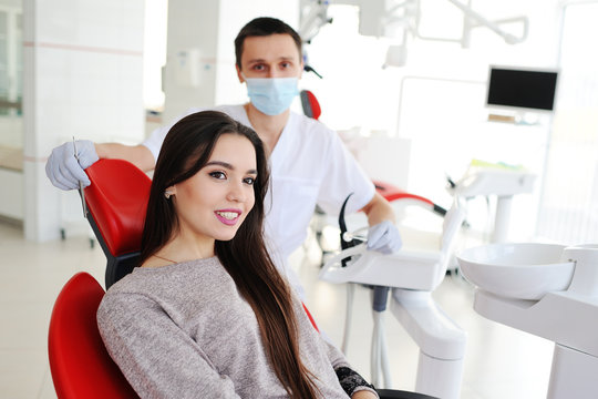 beautiful young girl smiling on the background of the dentist. dentist examines teeth attractive girl.