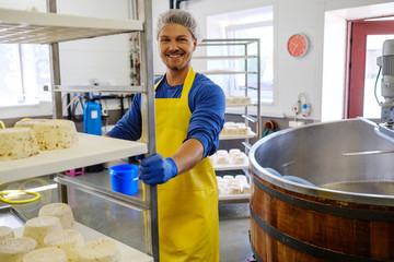 Handsome cheesemaker making curd cheese in his factory