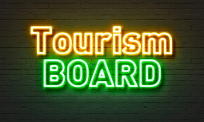 Tourism board neon sign on brick wall background.
