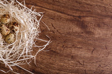 Quail eggs in straw nest. Natural organic eco food. Wooden rustic background.