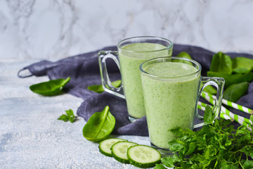 Obraz na płótnie Canvas Green vegetable smoothie with avocado, cucumber and spinach on a gray background