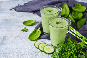 Green vegetable smoothie with avocado, cucumber and spinach on a gray background