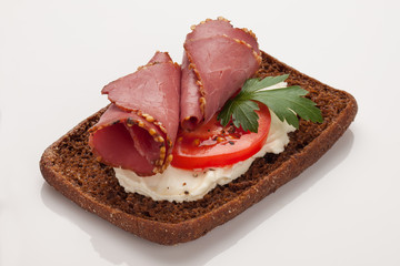 Rye bread sandwich with cream cheese, ham, tomato and parsley. On white background with reflection.