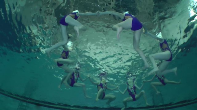 Synchronized swimming, team training, underwater view.

