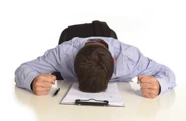 businessman sitting at office desk with hands on his head crying devastated and frustrated