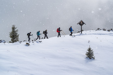 Group of unknown mountaineers walking on the snowy ridge of the Urslja gora mountain in the snow storm 