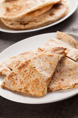 Crispy Quesadilla with Chicken and Sauce on white plate on dark wooden background angled shot