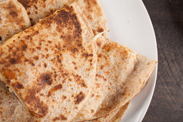 Crispy Quesadilla with Chicken and Sauce on white plate on dark wooden background above shot