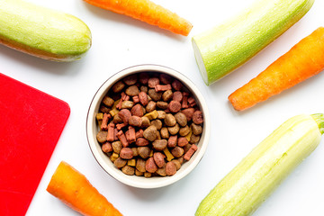 Dry dogfood with carrot and zucchini on table background top view