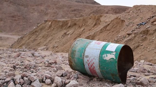 Old green rusty cask in desert. Iron barrel lies on the stony ground in Aqaba, Jordan