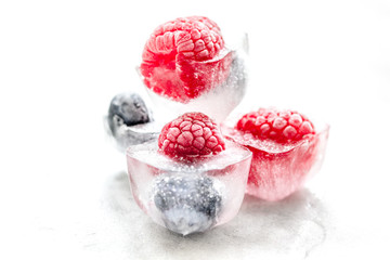 Icecubes with frozen berries on white background