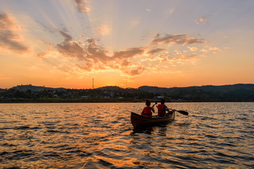 Unidentified traveler boating in the lake in sunset time