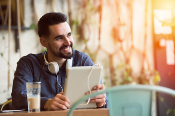 Handsome Modern Man using Tablet in Coffee Shop 