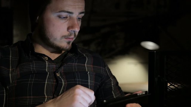 Man using tablet computer in cafe in the night