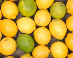 Ripe organic limes and lemons in wooden vintage tray like background
