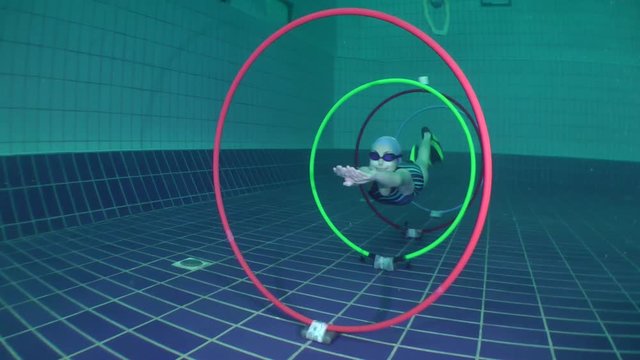 Training for freediving, the girls swim through the rings installed on the bottom of the pool.

