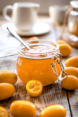 kumquat on plate and jam in jar at wooden table