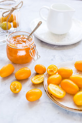 kumquat on plate and jam in jar at gray background