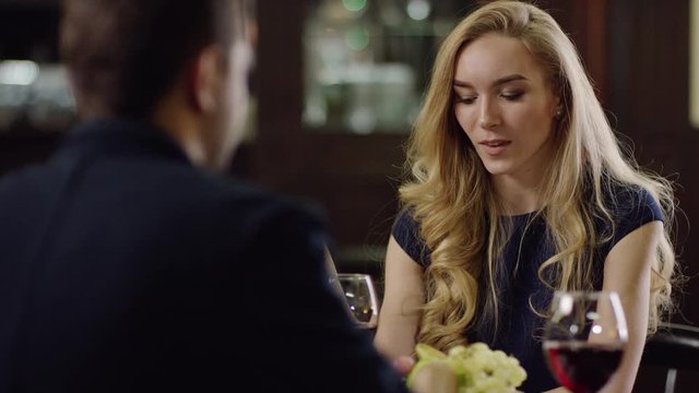 man and woman cheering with red wine in restaurant at the date