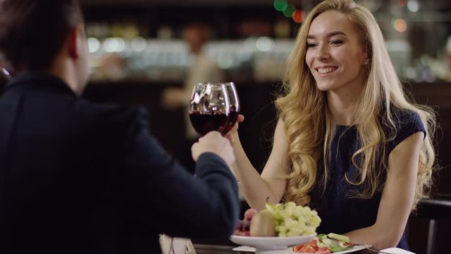 man and woman cheering with red wine